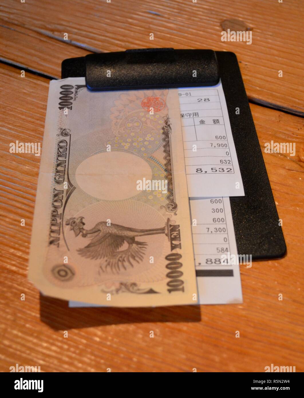 Japanese yen on a bill plate in a restaurant in Tokyo with a receipt Stock Photo