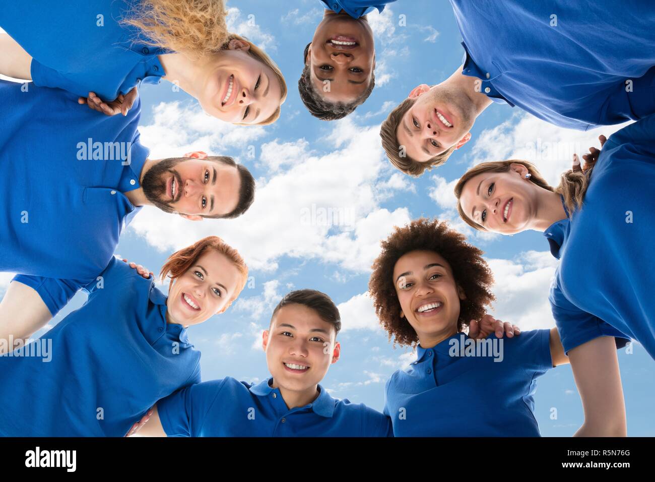 Happy Multiracial Janitors Forming Huddle Stock Photo
