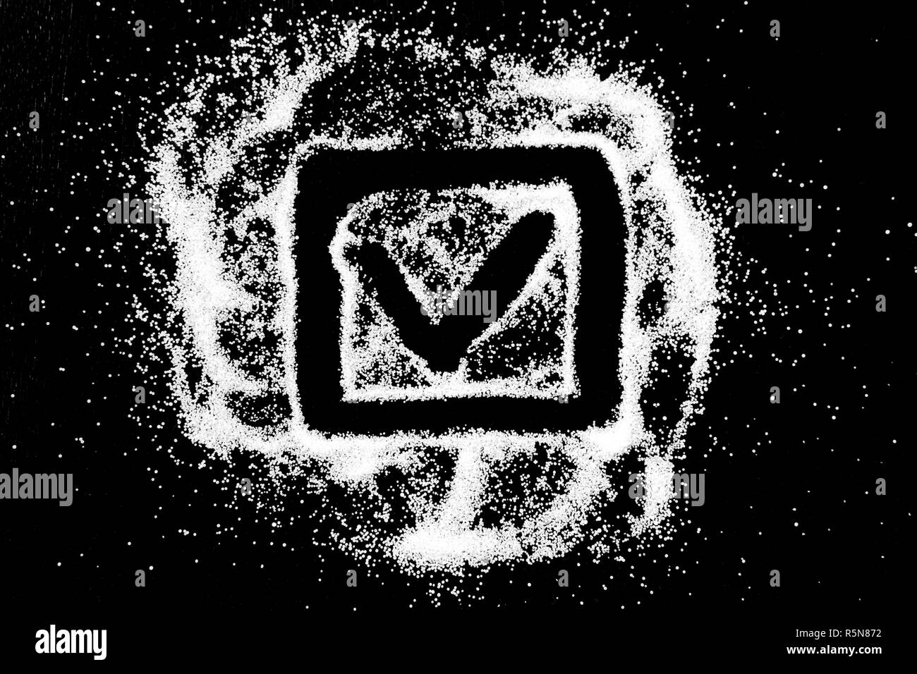Checking mark symbol in checkbox drawing by finger on white snow salt powder spot cloud in center on black background. Tick concept with place for text. Copy space. Stock Photo