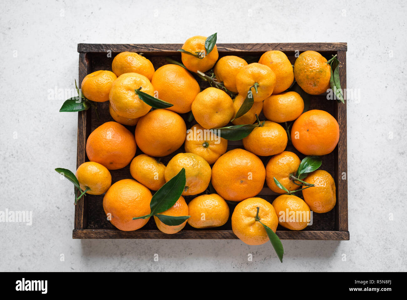Tangerines (oranges, clementines, citrus fruits) with green leaves in
