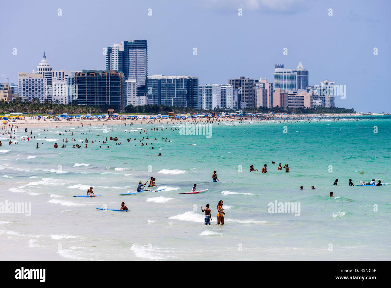 Miami Beach Florida,Atlantic Ocean,water,public beach,seashore,surfer,man men male,woman female women,swim,wade,shallow,walk,shoreline,hotels,city sky Stock Photo