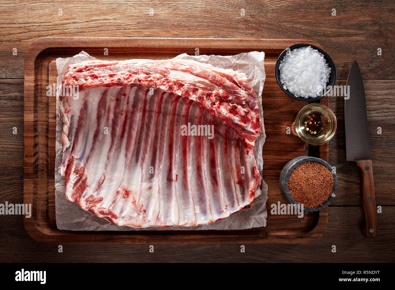 Raw rack of lamb ribs on white cooking paper and wooden cutting board