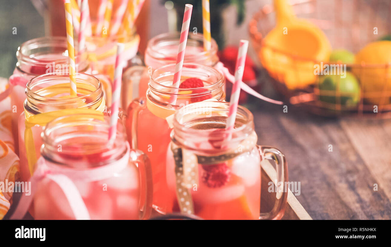 Raspberry lemonade garnished with fresh lemon and raspberries in drinking mason jars. Stock Photo