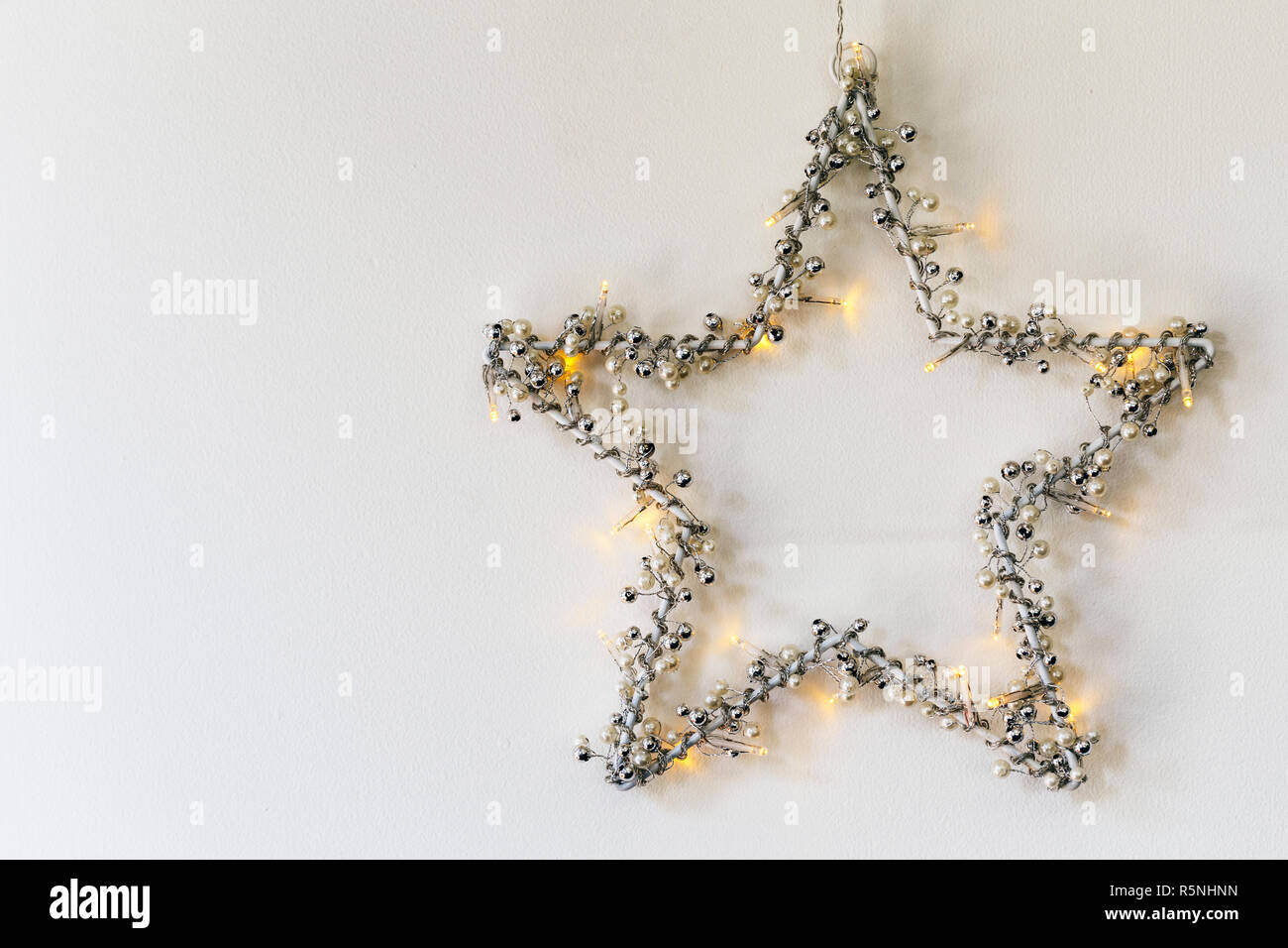 Christmas star with lights hanging on white wall Stock Photo