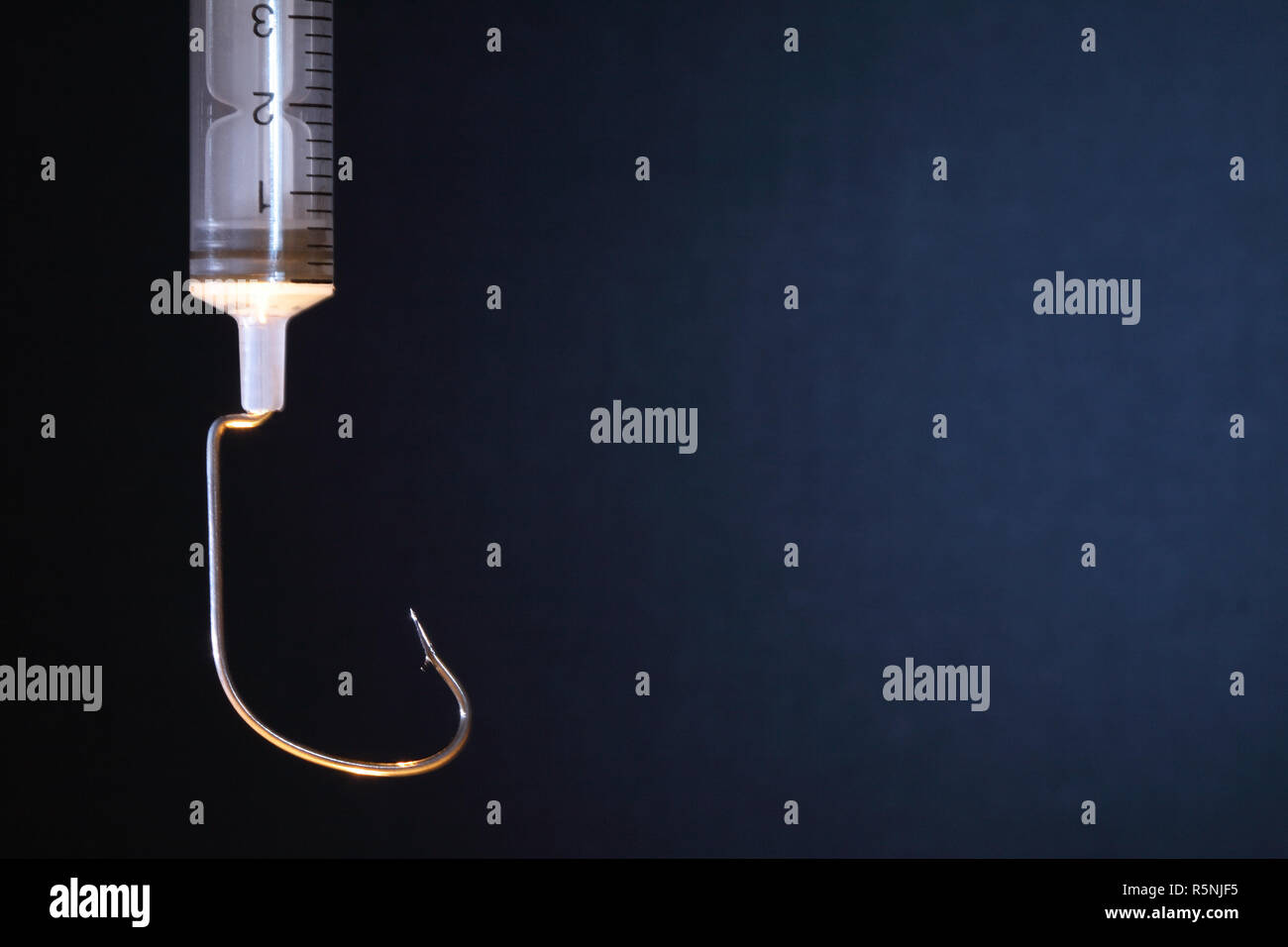 Closeup of syringe with fish hook as surgical needle on dark background Stock Photo