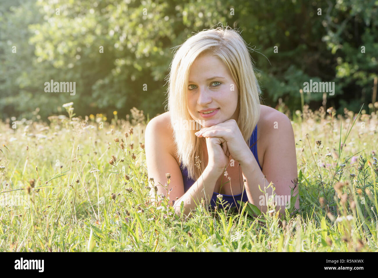 Portrait of young woman lying in the grass Stock Photo - Alamy