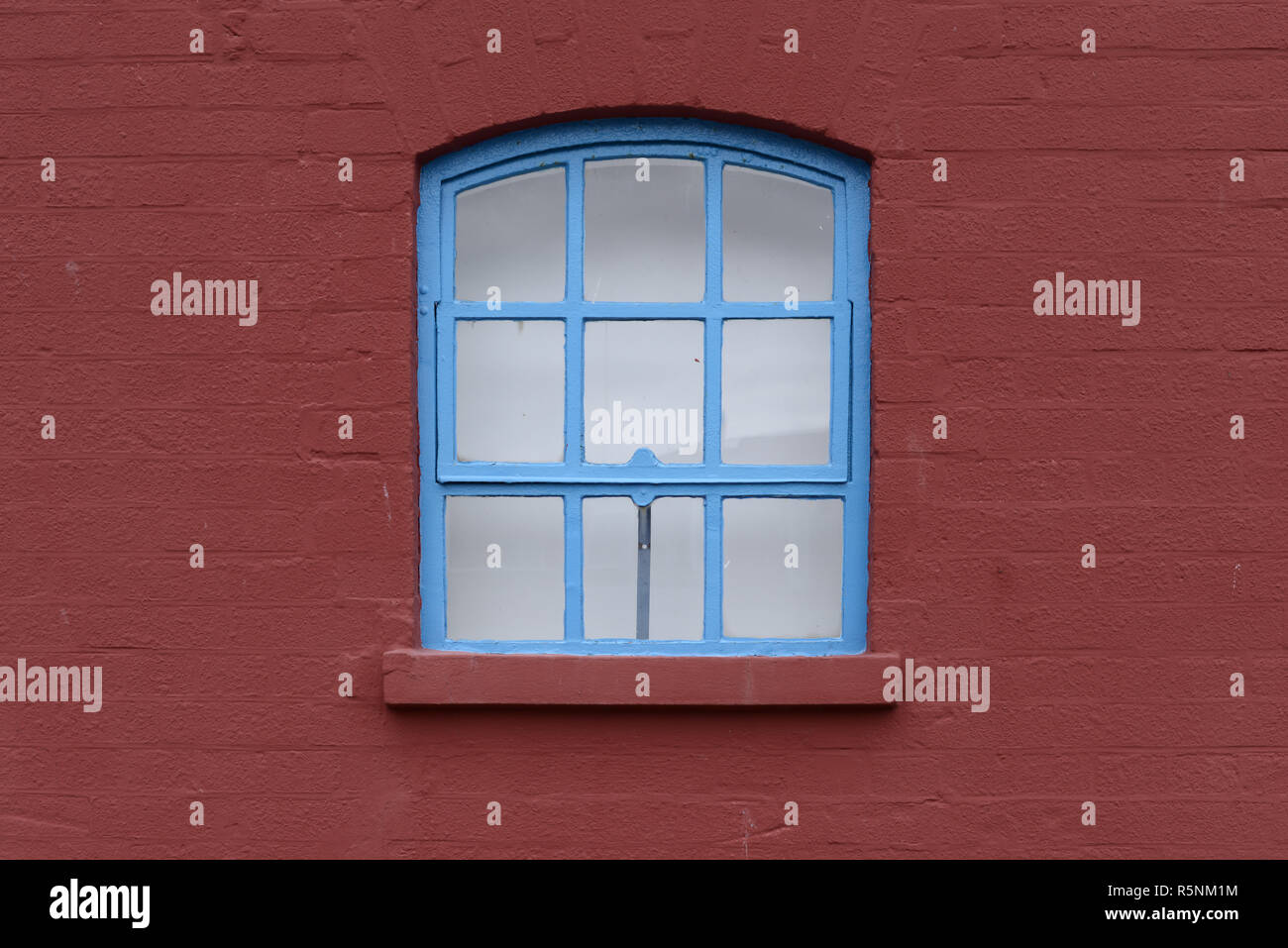 blue window in red brick wall Stock Photo