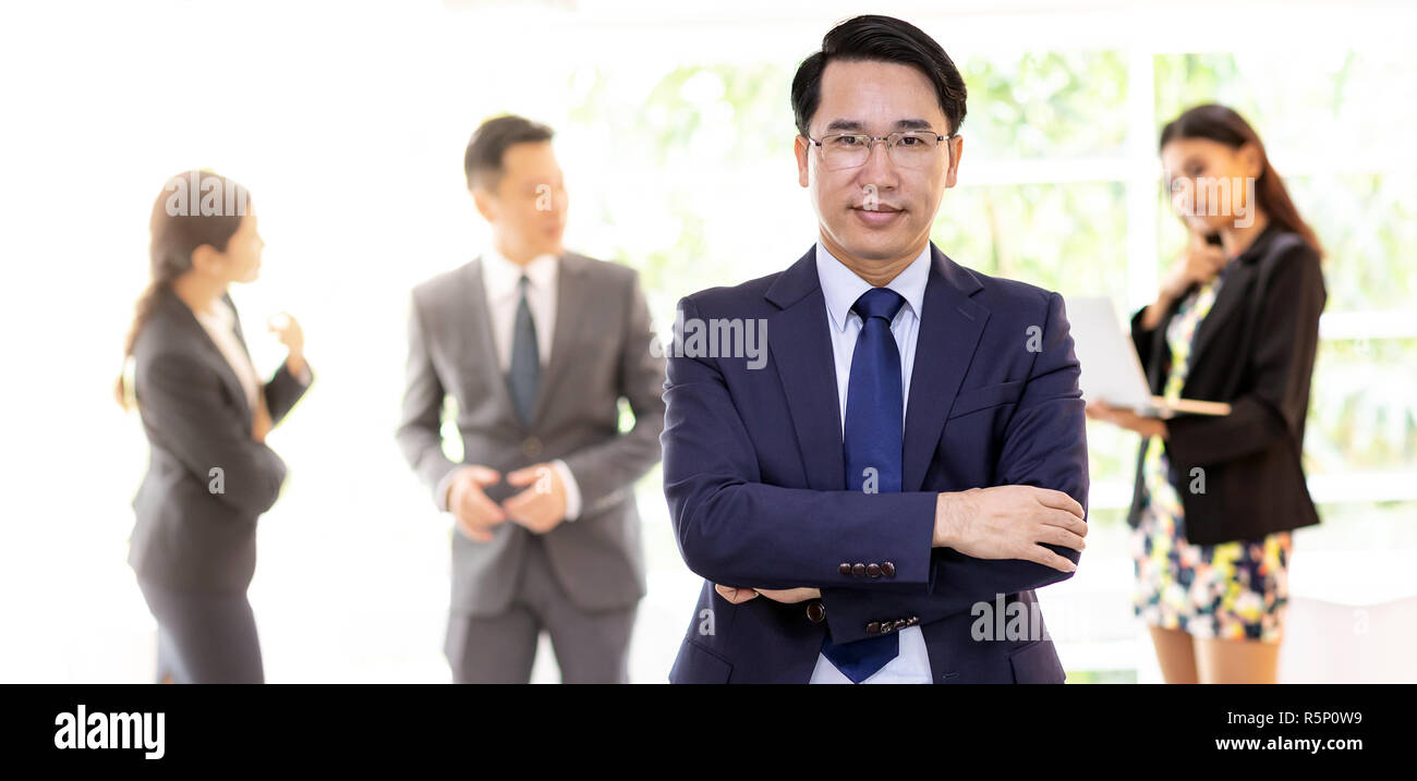 Portrait of asian businessman with business team in background at office window using for coporate working background, panoramic web banner compositio Stock Photo