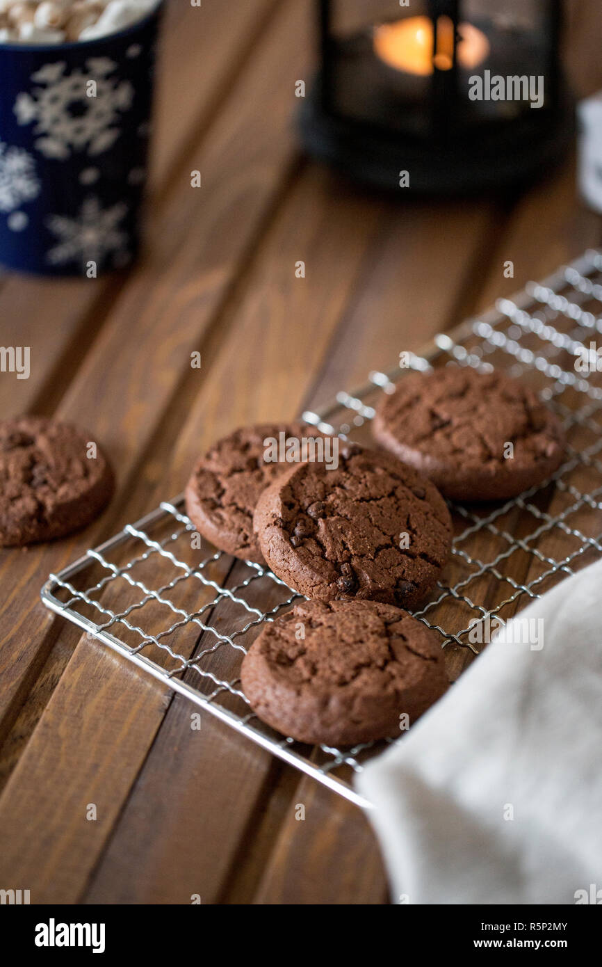Chocolate cookies at metal grill, with napkin and blue cup near on wood background. Christmas composition Stock Photo