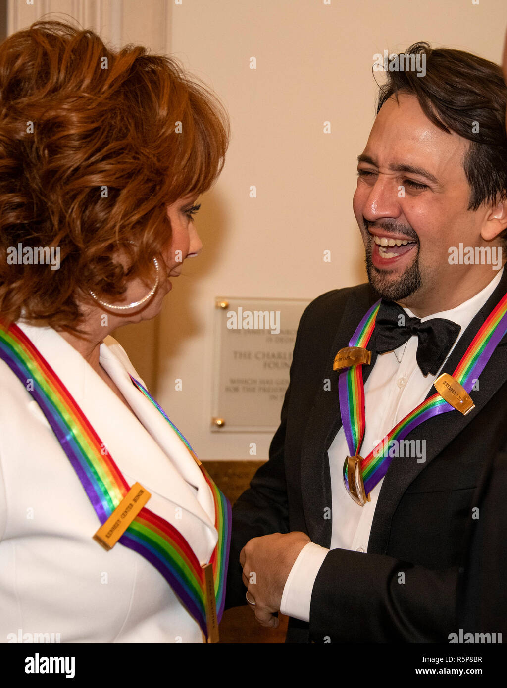Reba McEntire, left, and Lin-Manuel Miranda, right, two of the recipients of the 41st Annual Kennedy Center Honors converse prior to posing for a group photo following a dinner hosted by United States Deputy Secretary of State John J. Sullivan in their honor at the US Department of State in Washington, DC on Saturday, December 1, 2018. The 2018 honorees are: singer and actress Cher; composer and pianist Philip Glass; Country music entertainer Reba McEntire; and jazz saxophonist and composer Wayne Shorter. This year, the co-creators of Hamilton,- writer and actor Lin-Manuel Miranda; director Stock Photo