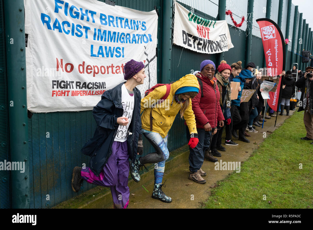 Milton Ernest, Bedford, UK. 1st December 2018. Yarls Wood Immigration Removal Centre ‘Suround Yarls Wood - Shut Down Yarls Wood and all Detention Centres’ demonstration. Hundreds braved the poor weather to join the protest at the remotely situated Yarls Wood IRC. Incarcerated women waved desperately at windows and their mobile phone conversations were relayed via the PA system outside the security fence. Speakers included those who had previously been imprisoned in Yarls Wood. This was the 15th Yarls Wood demonstration organised by Movement for Justice. Credit: Steve Bell/Alamy Live News Stock Photo
