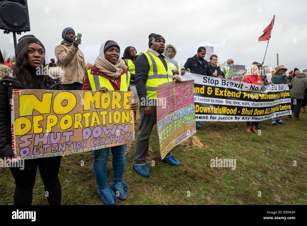 Milton Ernest, Bedford, UK. 1st December 2018. Yarls Wood Immigration Removal Centre ÔSuround Yarls Wood - Shut Down Yarls Wood and all Detention CentresÕ demonstration. Hundreds braved the poor weather to join the protest at the remotely situated Yarls Wood IRC. Incarcerated women waved desperately at windows and their mobile phone conversations were relayed via the PA system outside the security fence. Speakers included those who had previously been imprisoned in Yarls Wood. This was the 15th Yarls Wood demonstration organised by Movement for Justice. Credit: Steve Bell/Alamy Live News Stock Photo
