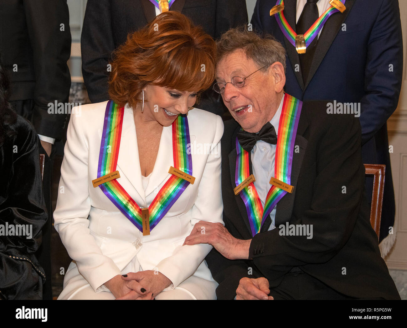 Washington, USA. 1st Dec 2018. Reba McEntire, left, and Philip Glass two of the recipients of the 41st Annual Kennedy Center Honors, converse as they pose for a group photo following a dinner hosted by United States Deputy Secretary of State John J. Sullivan in their honor at the US Department of State in Washington, DC on Saturday, December 1, 2018. Credit: MediaPunch Inc/Alamy Live News Stock Photo