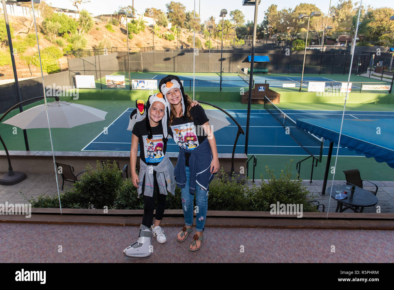 California, USA. 1st Dec 2018. Author, Ivor Davis' granddaughters posing in penguin costume overlooking tennis courts at book signing at Pierpont Racquet Club in Ventura, California, USA on December 1, 2018. Credit: Jon Osumi/Alamy Live News Stock Photo