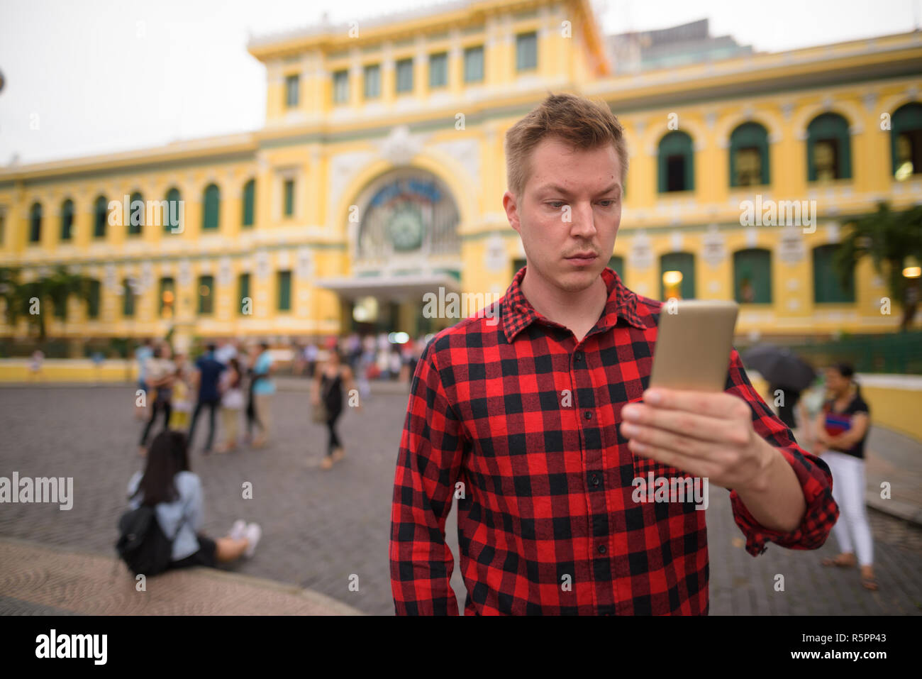 Tourist man using phone in front of Saigon Central Post Office Stock Photo