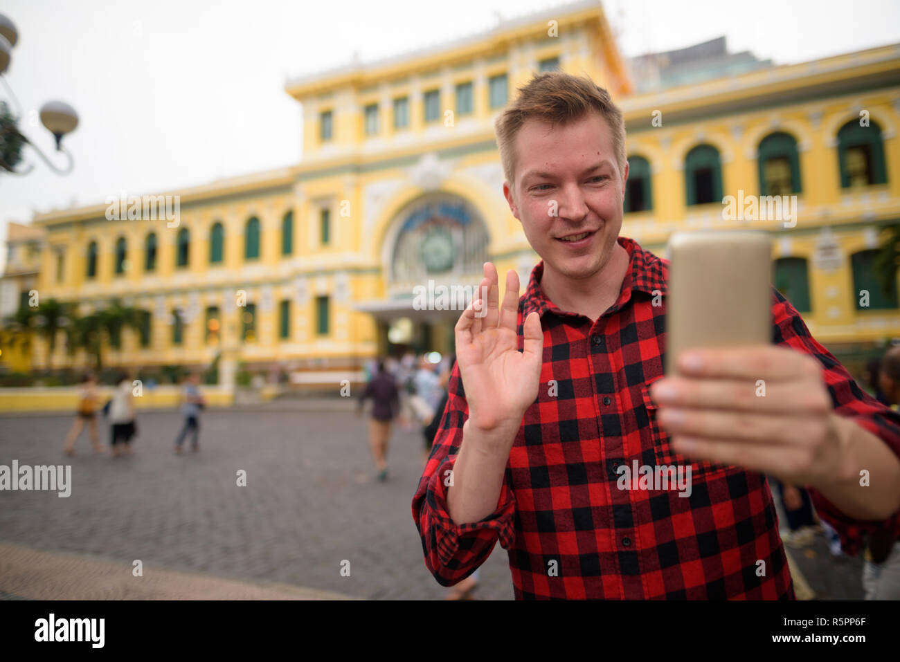 Tourist man using phone in front of Saigon Central Post Office Stock Photo