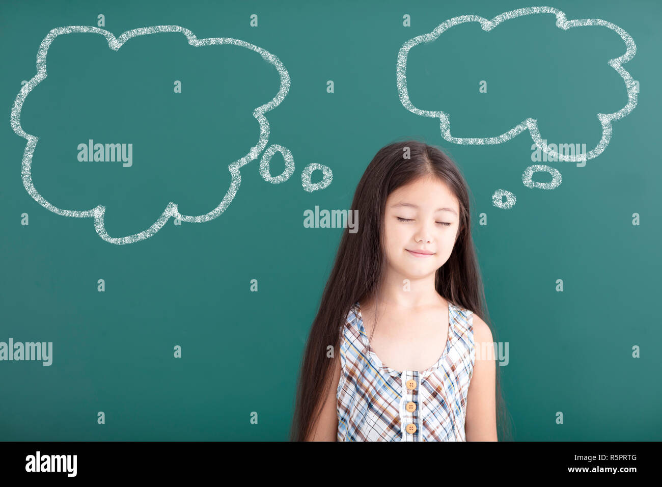 beautiful little girl thinking before chalkboard Stock Photo