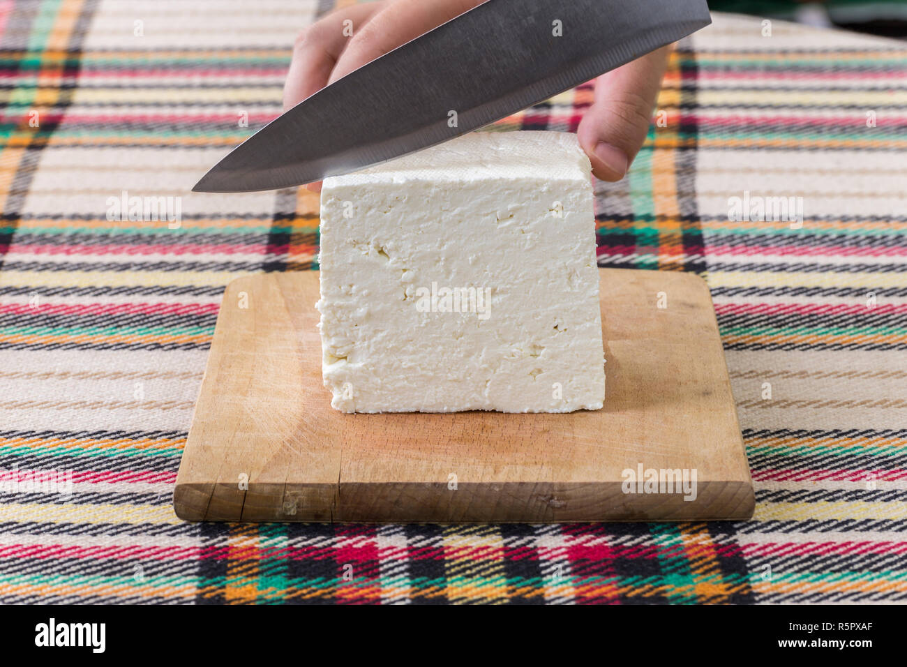 Cutting traditional bulgarian salty white cheese with a knife. First person point of view concept. Stock Photo