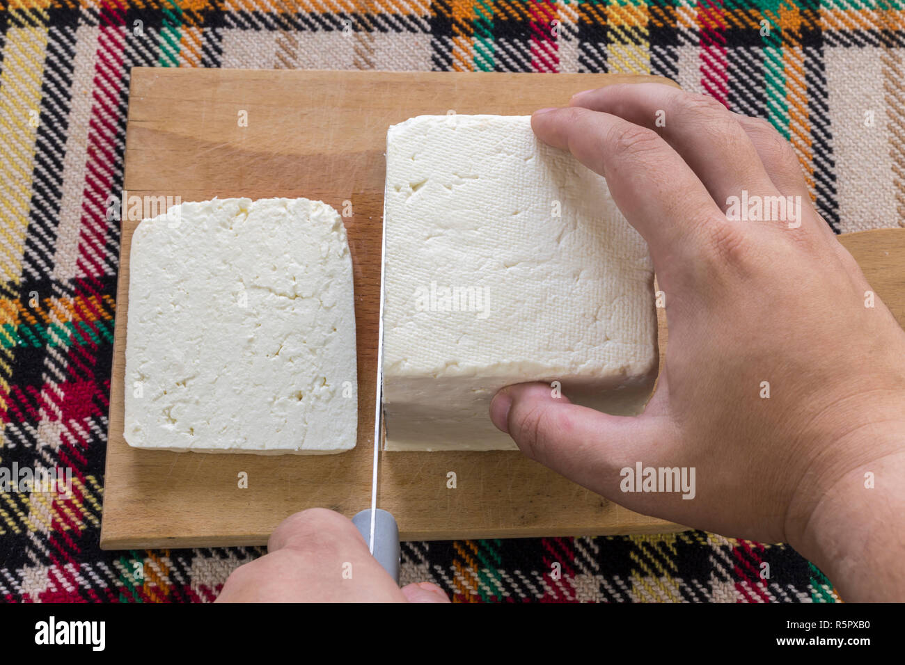 Cutting traditional bulgarian salty white cheese with a knife. First person point of view concept. Stock Photo