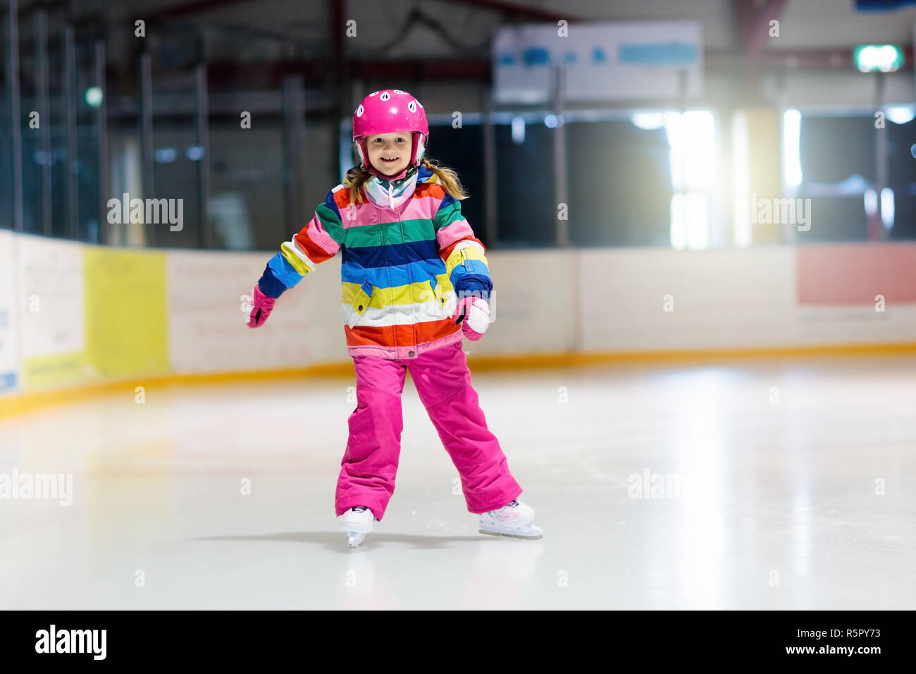 Child skating on indoor ice rink. Kids skate. Active family sport