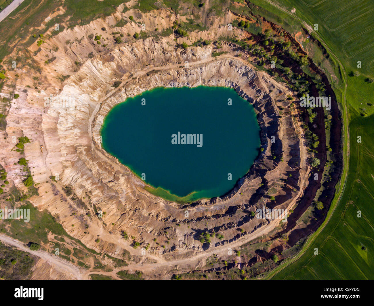 Aerial view of a crater created by mining machines and filled up with water creating an artificial lake. Stock Photo