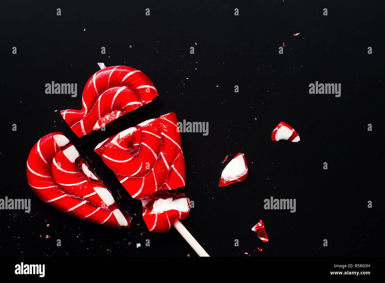 Broken lollipop in shape of heart on dark background with copy space ...