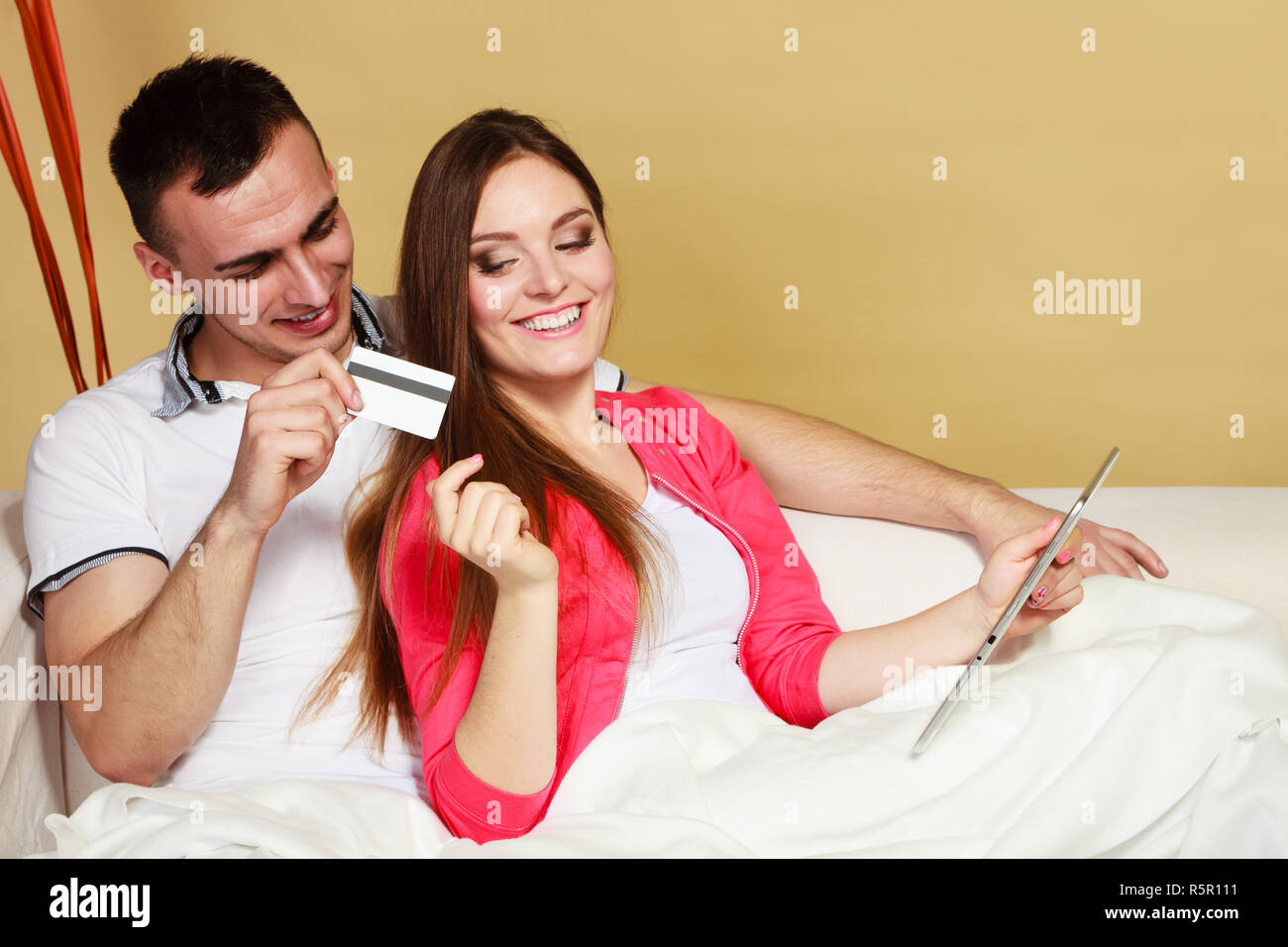 Shopping consumerism leisure and people concept. Young couple with tablet pc and credit card on sofe at home doing shopping on internet Stock Photo
