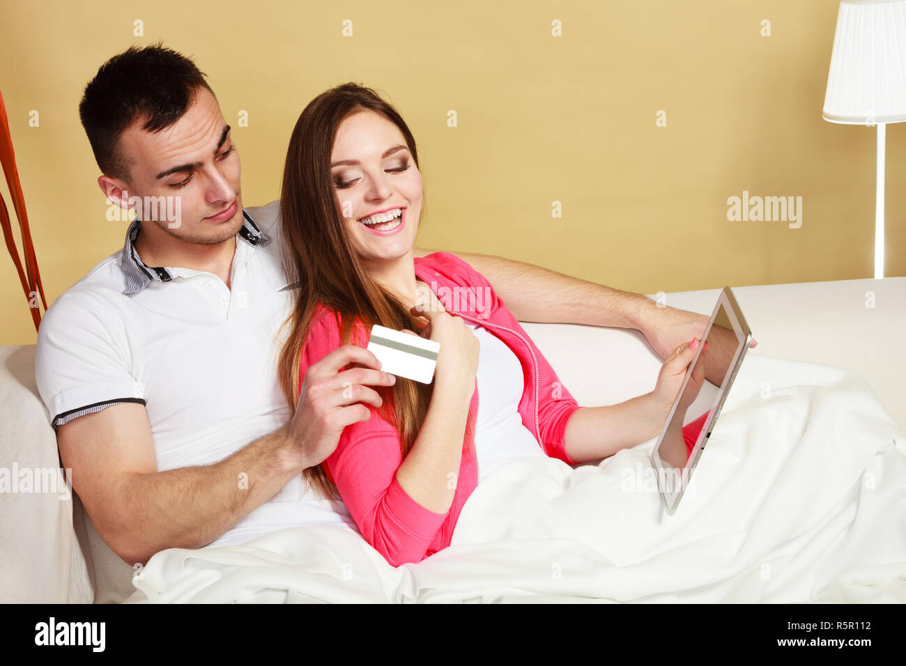 Shopping consumerism leisure and people concept. Young couple with tablet pc and credit card on sofe at home doing shopping on internet Stock Photo