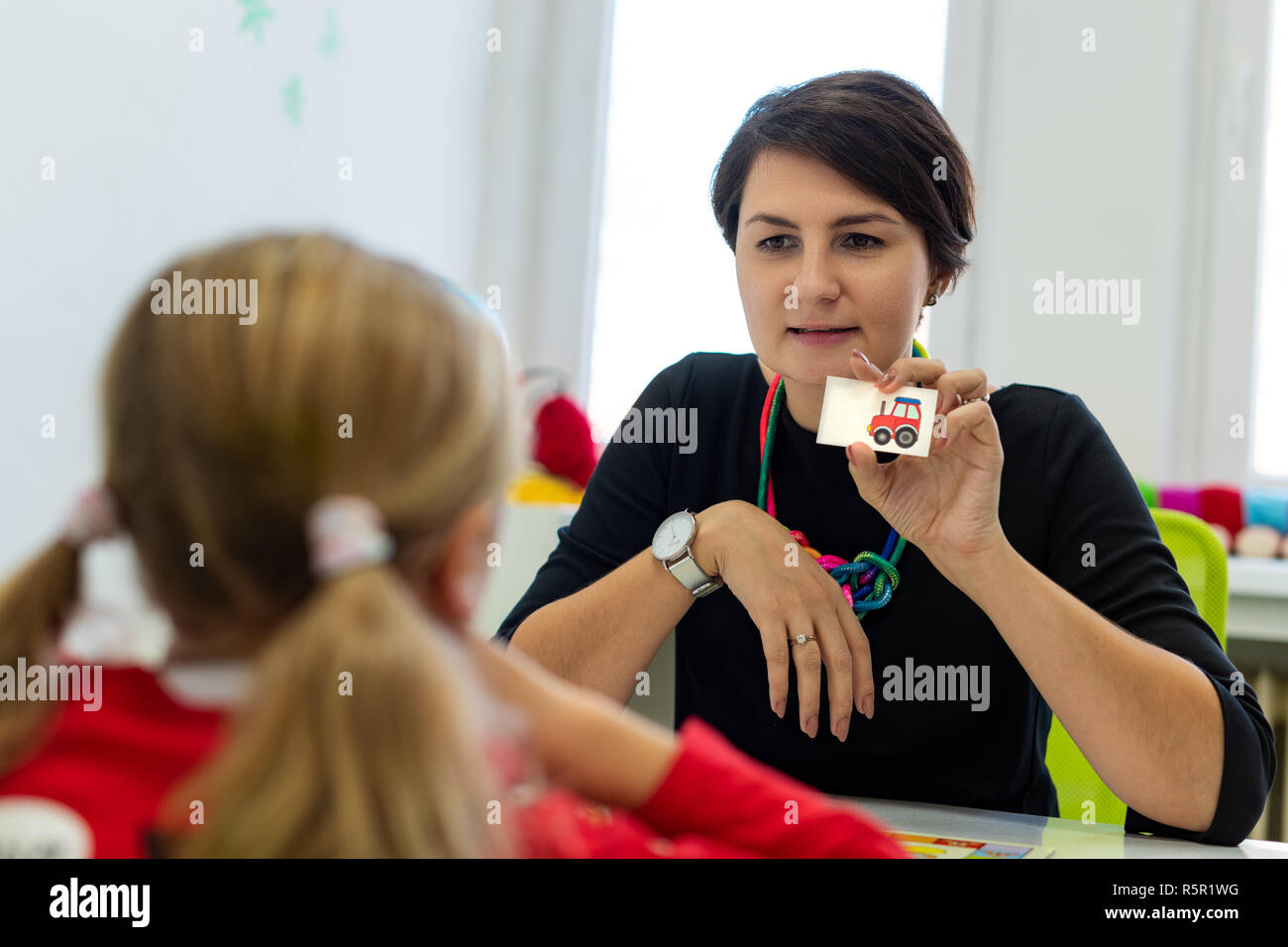 Elementary Age Girl in Child Occupational Therapy Session Doing Playful Exercises With Her Therapist. Stock Photo