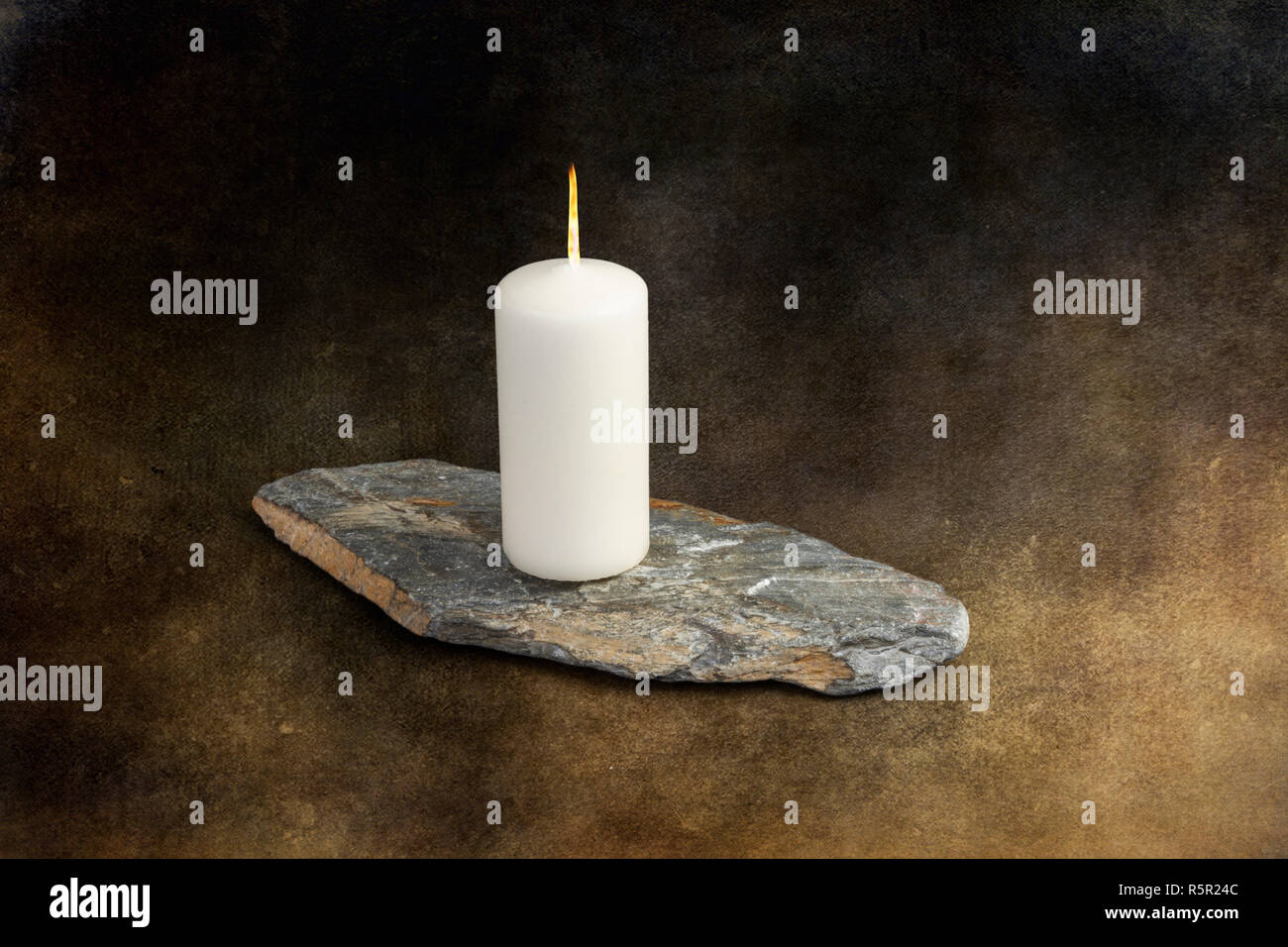 Flaming candle on a piece of slate Stock Photo