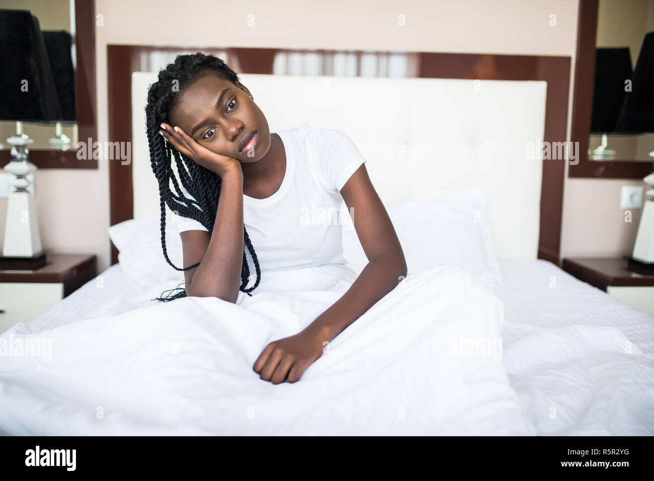 Woman sitting on her bed looking at the camera Stock Photo - Alamy