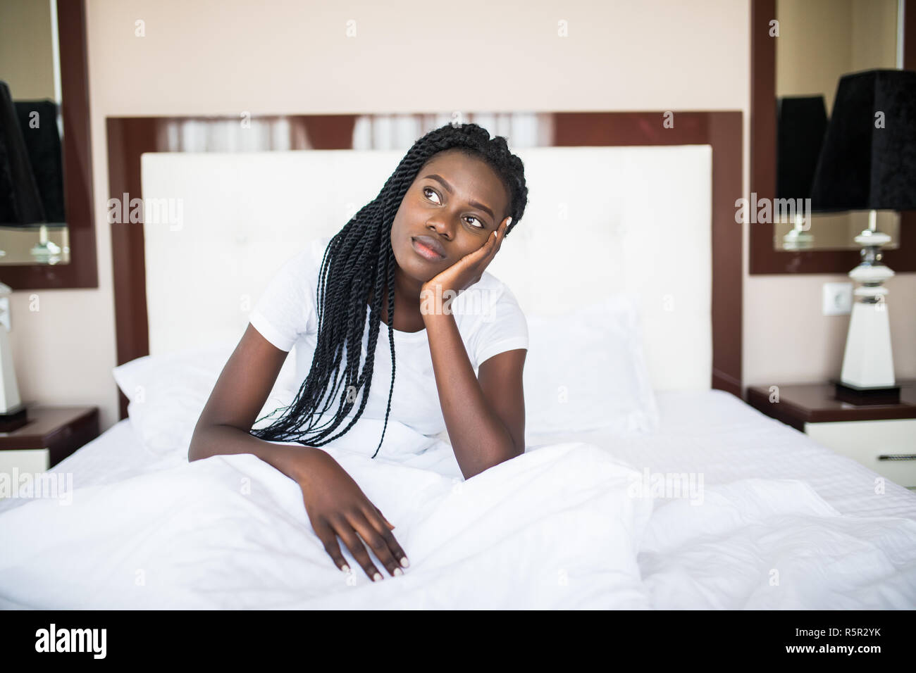 Woman sitting on her bed looking at the camera Stock Photo - Alamy