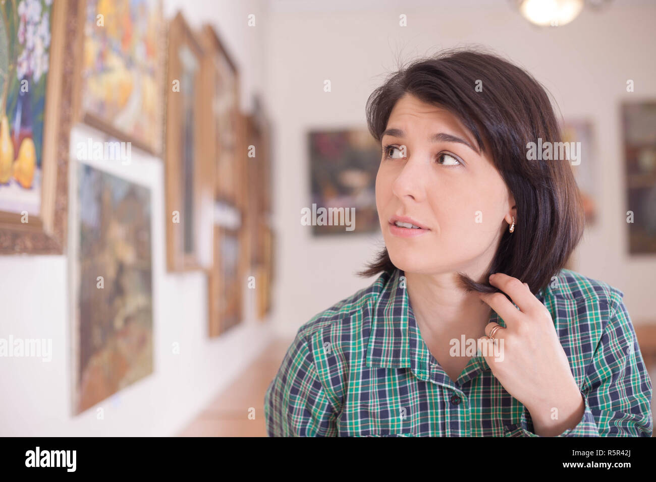A young beautiful woman looking at painting in an art gallery. Stock Photo