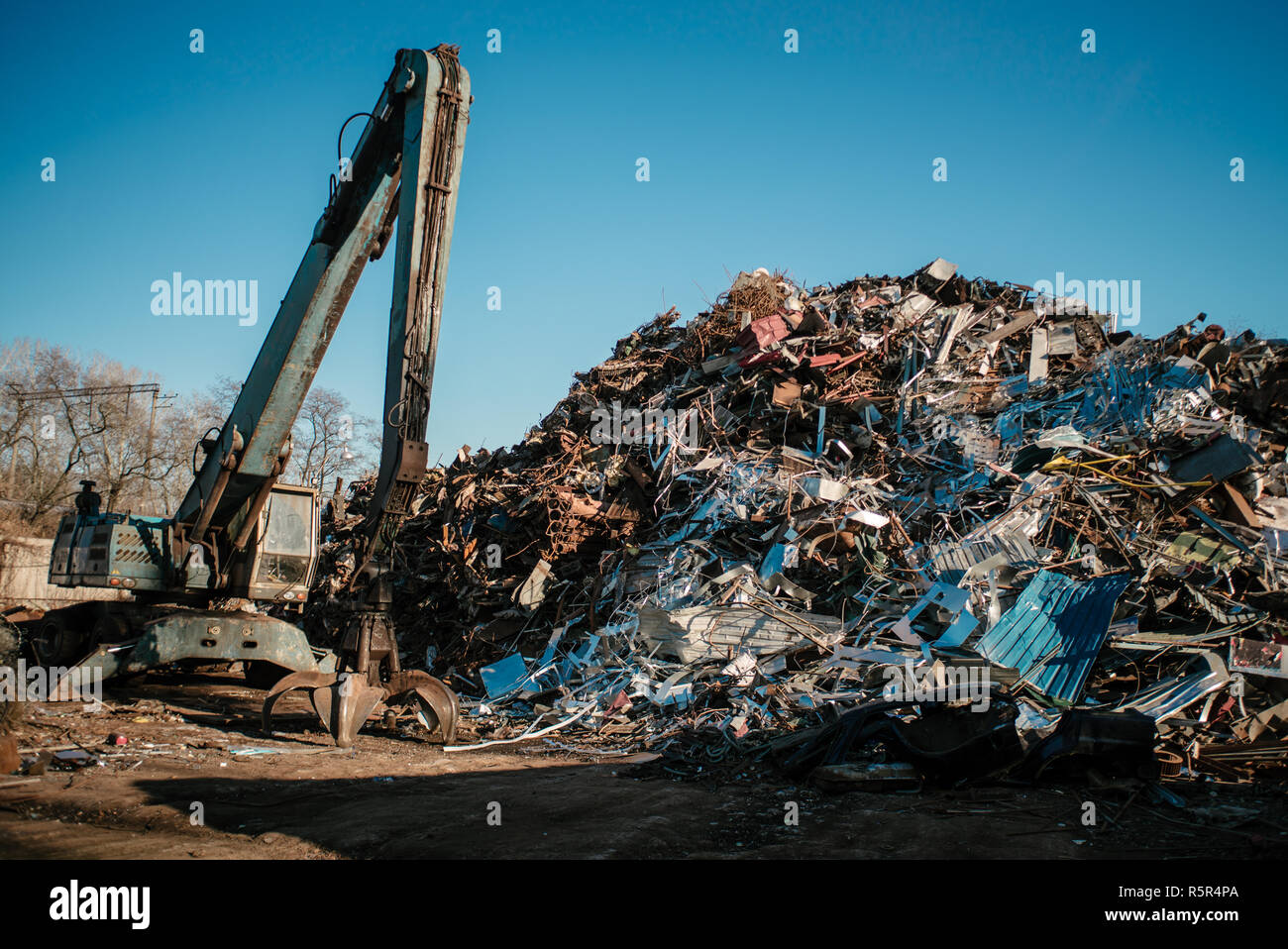 Recycling station. Metal dump with working crane and deep blue sky Stock Photo