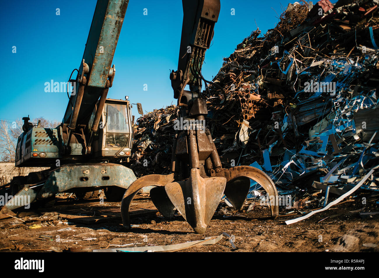 Recycling station. Metal dump with working crane and deep blue sky Stock Photo