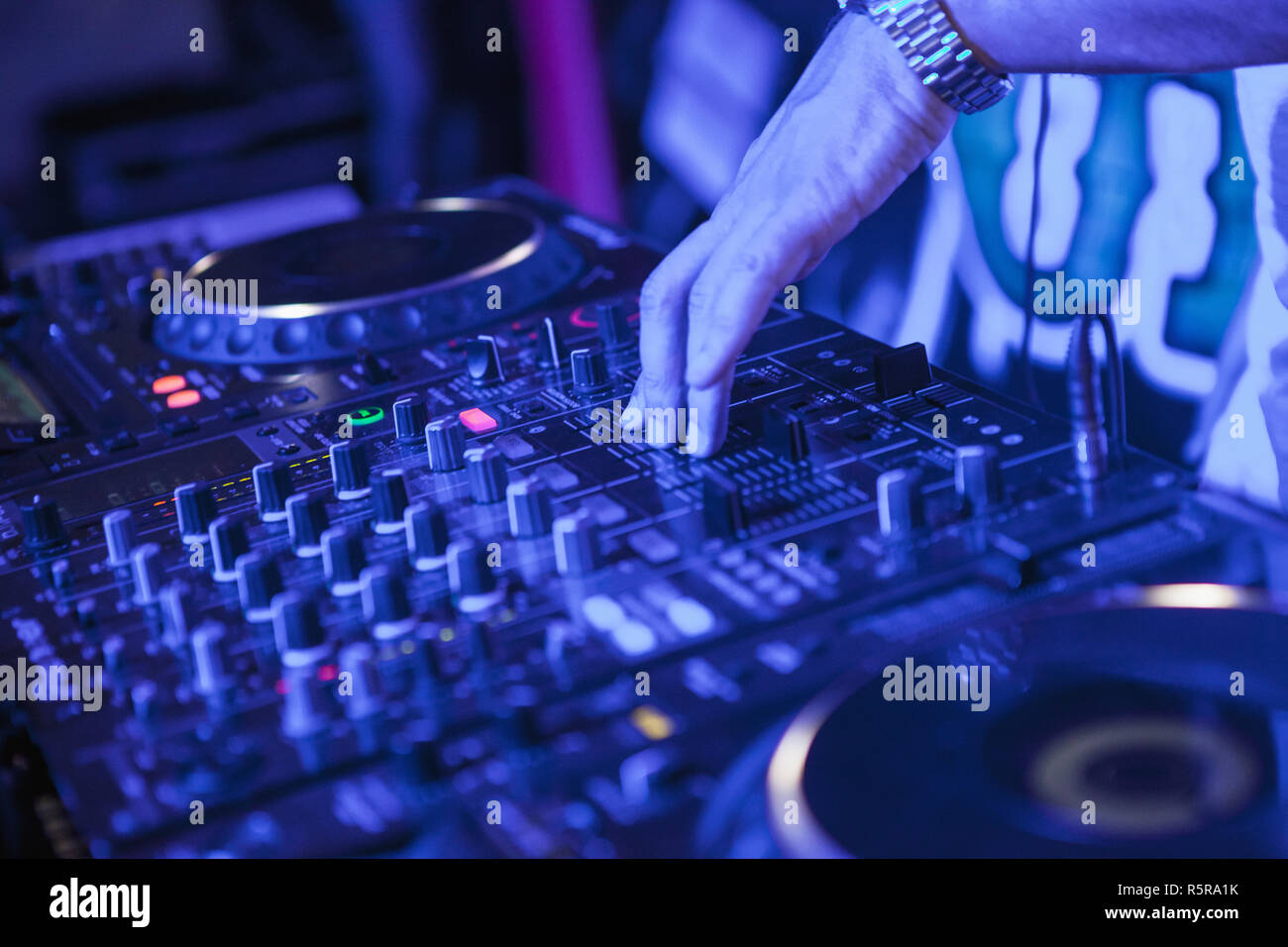 DJ playing music at mixer on colorful blurred background Stock Photo - Alamy