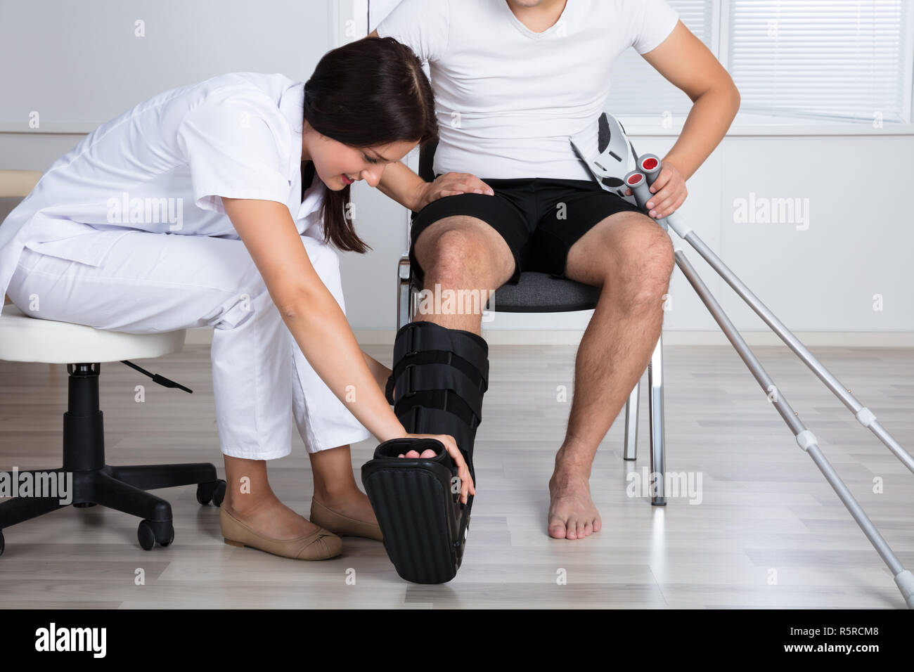 Female Doctor Putting Walking Brace On Person's Leg Stock Photo Alamy