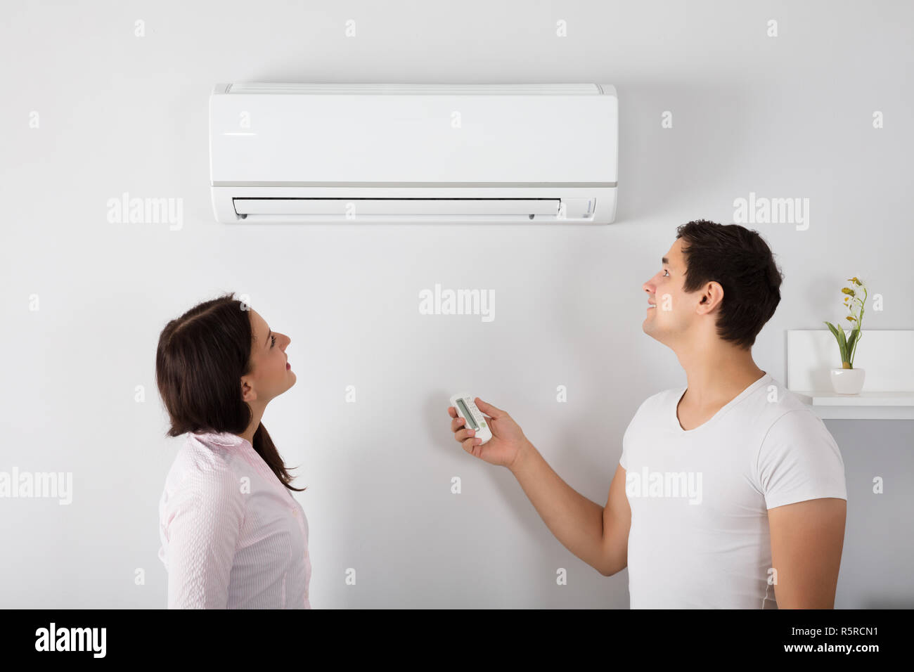 Couple Adjusting Temperature Of Air Conditioner Stock Photo Alamy