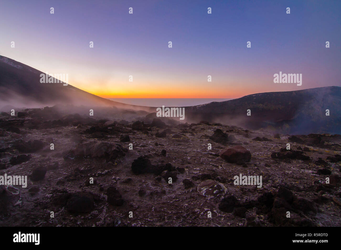 the first rays of sunshine on the central crater of etna. Stock Photo