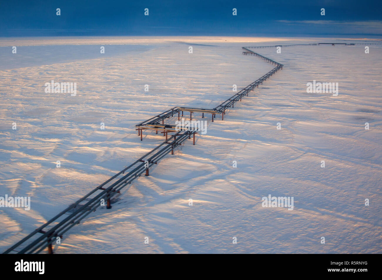 An elevated pipeline running above ground and the frozen tundra from Endicott oil production facility to the Alyaska 1 pipeline in Prudhoe Stock Photo