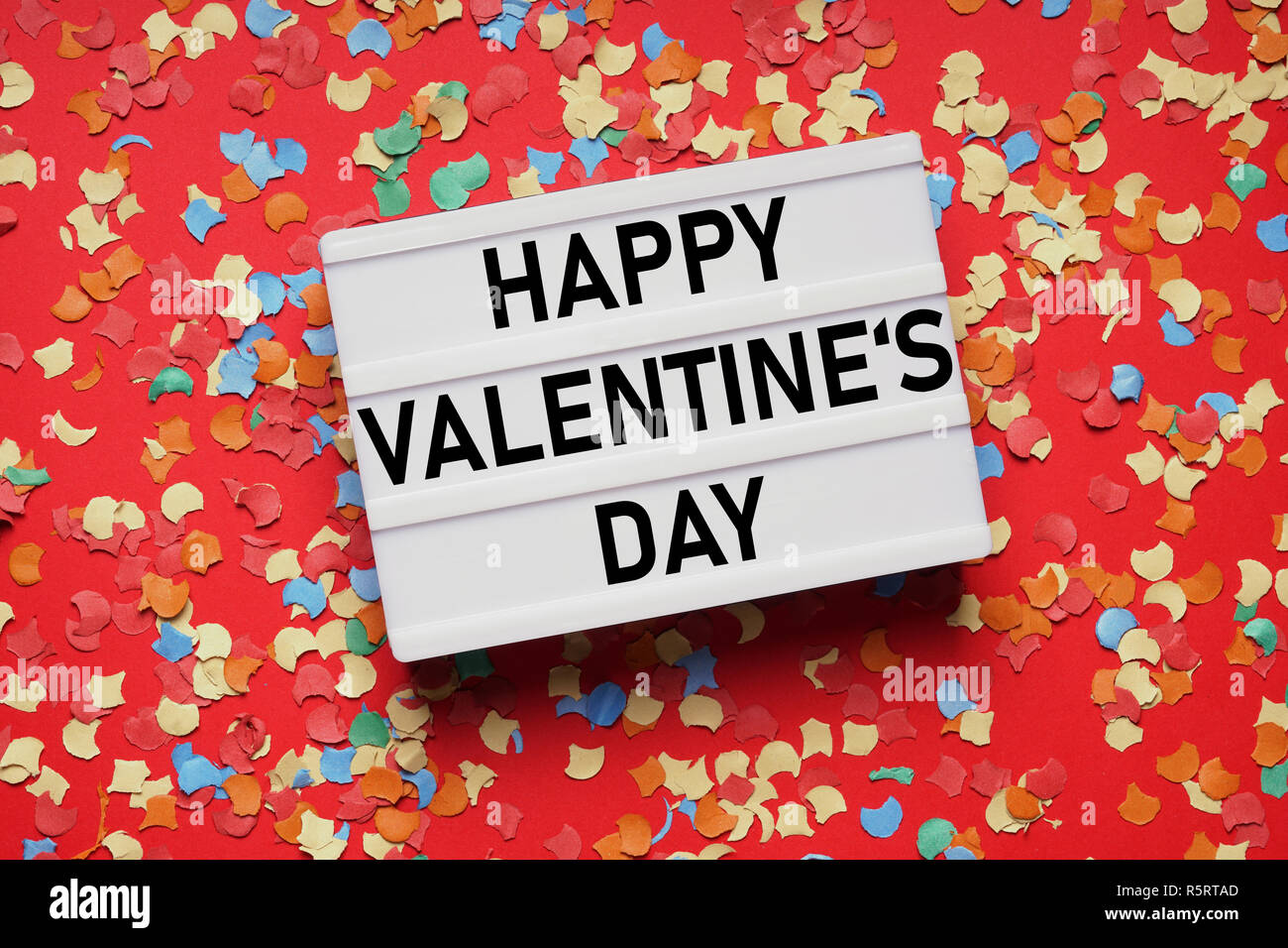 valentines day lightbox sign on red paper background with confetti Stock Photo