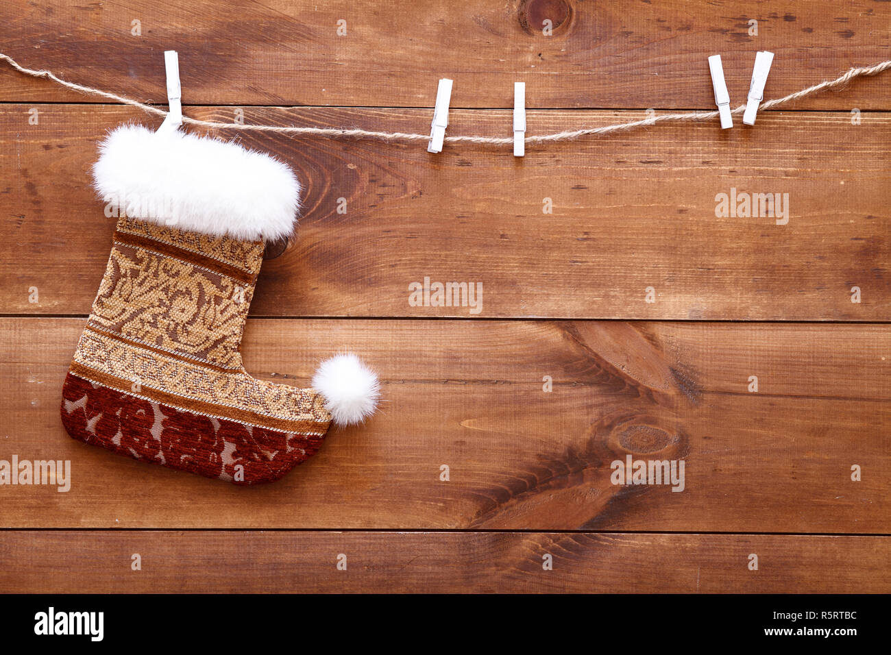 Christmas stocking hanging on brown wooden background, decorative xmas sock on wood table, buying presents for family sale, holiday decorations for Ne Stock Photo