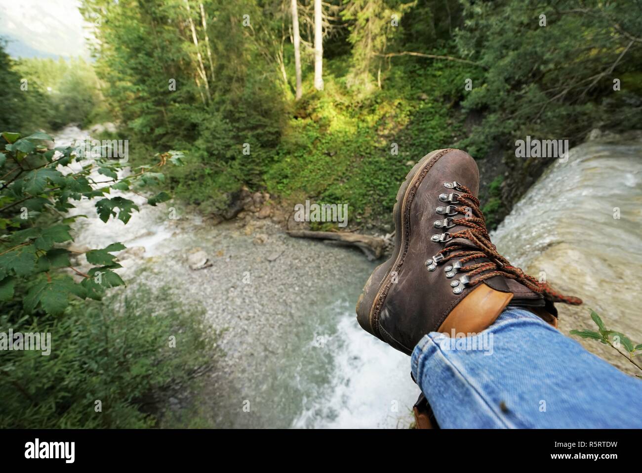young man at a waterfall,one sees the mountain boots Stock Photo