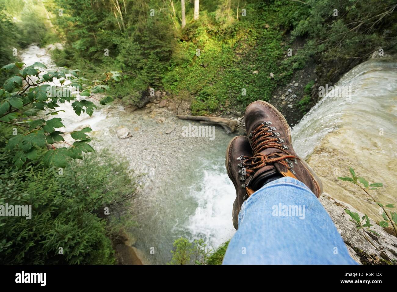 young man at a waterfall,one sees the mountain boots Stock Photo