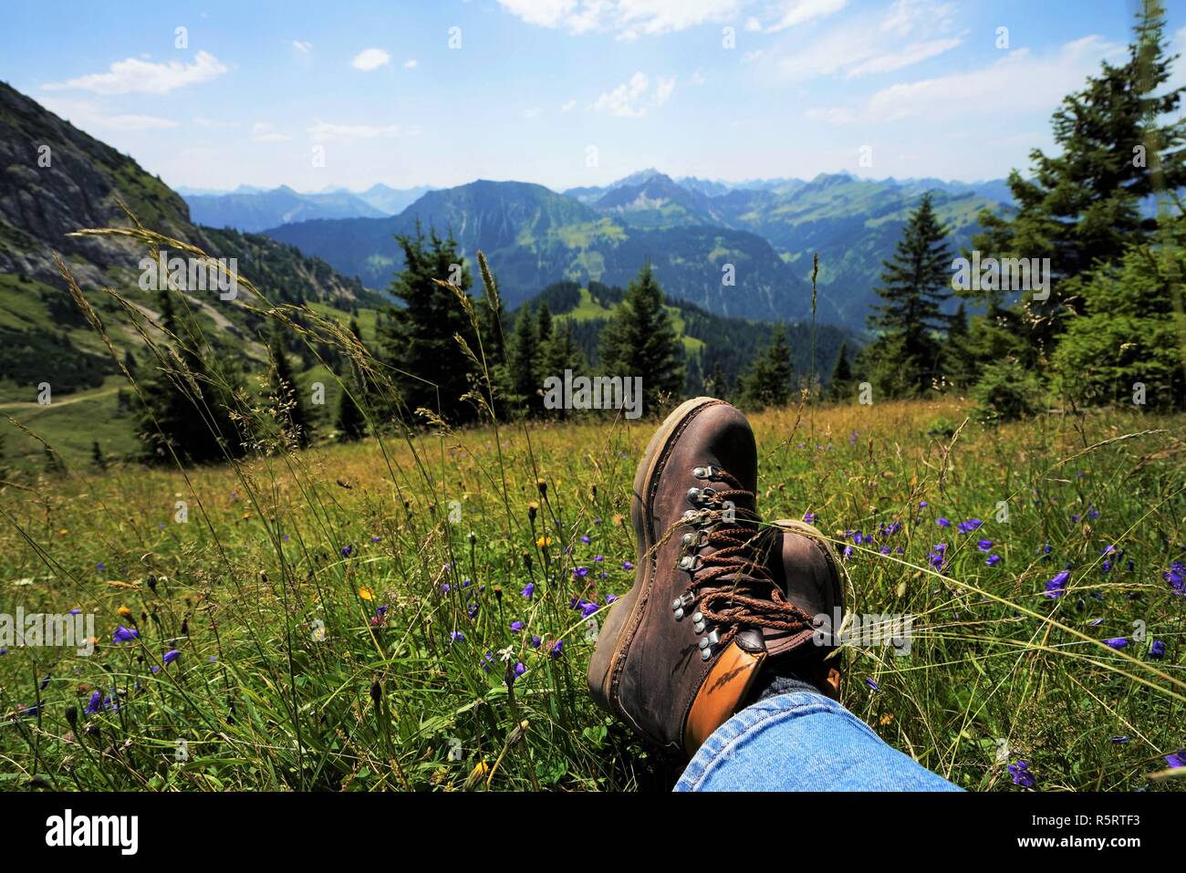 young man takes a break in the alps,one sees the mountain boots Stock Photo