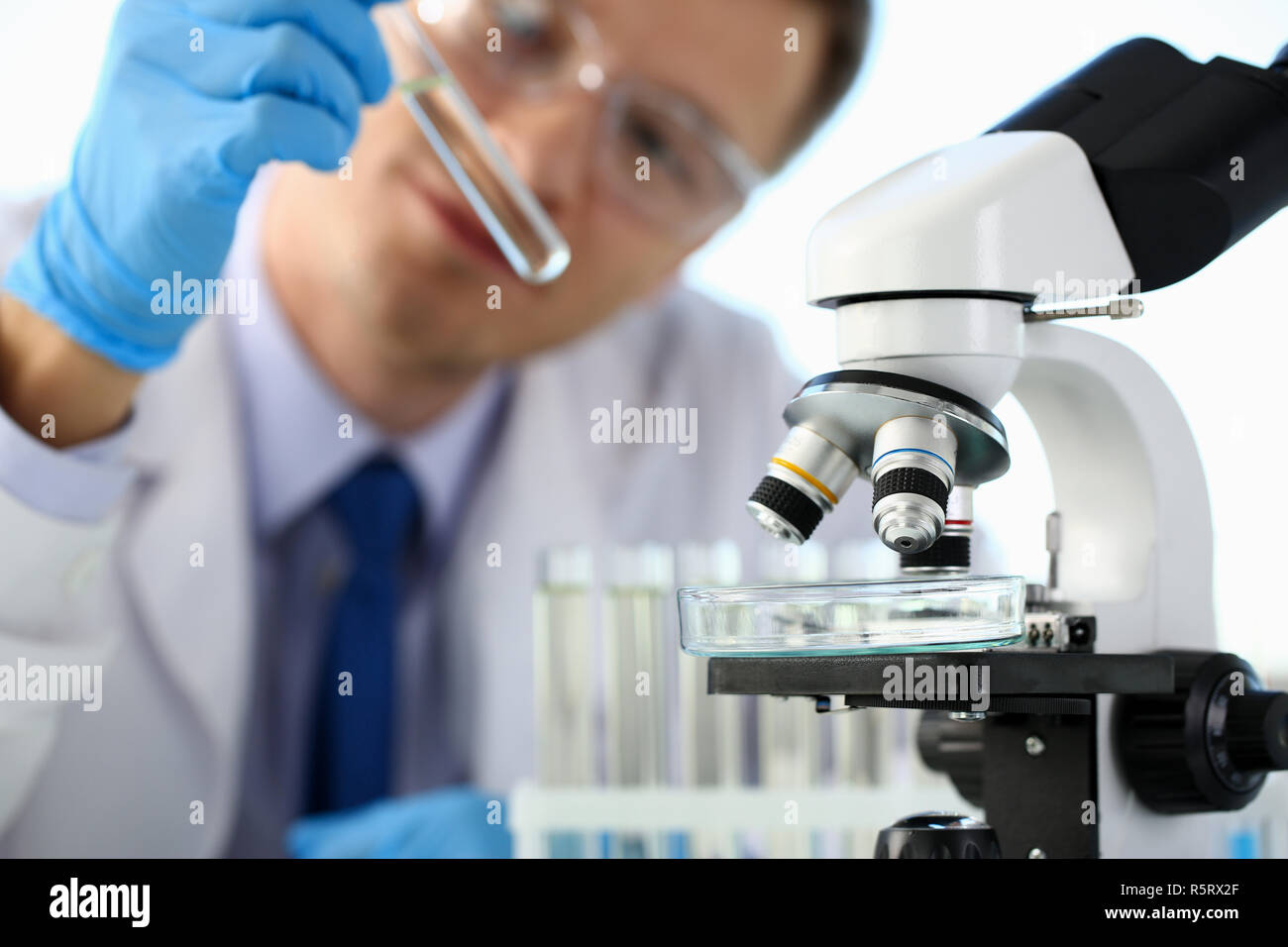 A male chemist holds test tube of glass in his hand Stock Photo