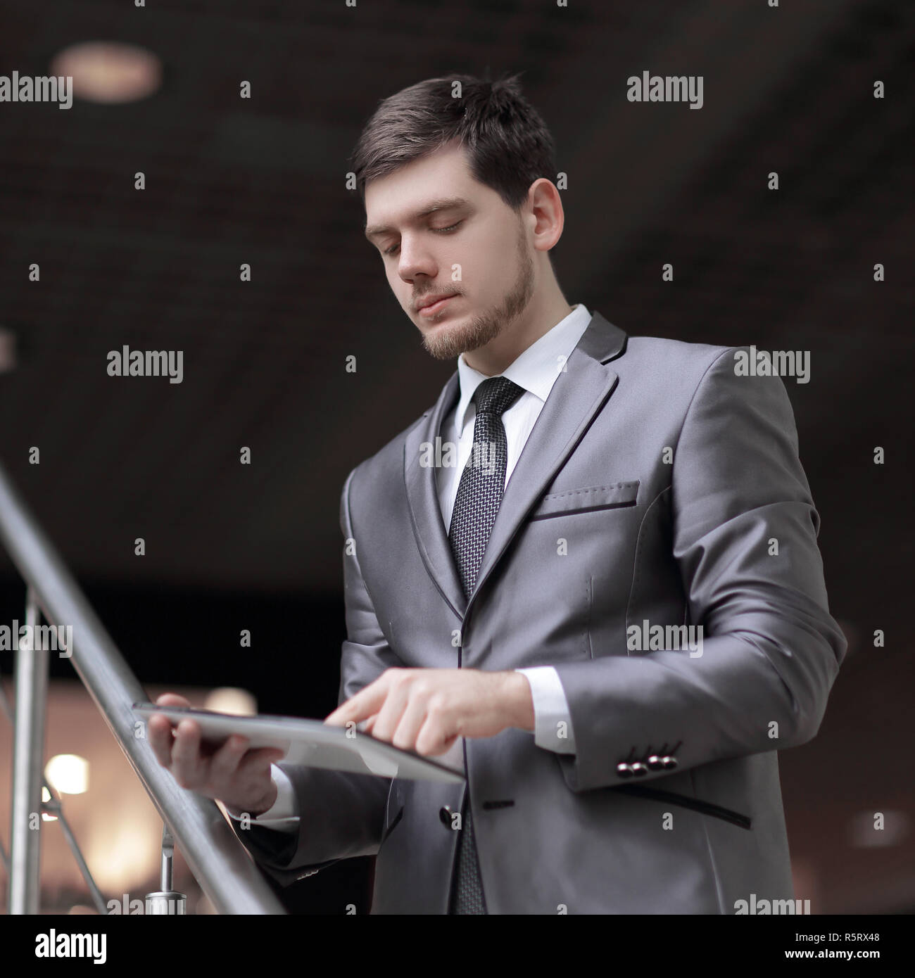 Handsome businessman standing on steps using tablet in office building Stock Photo