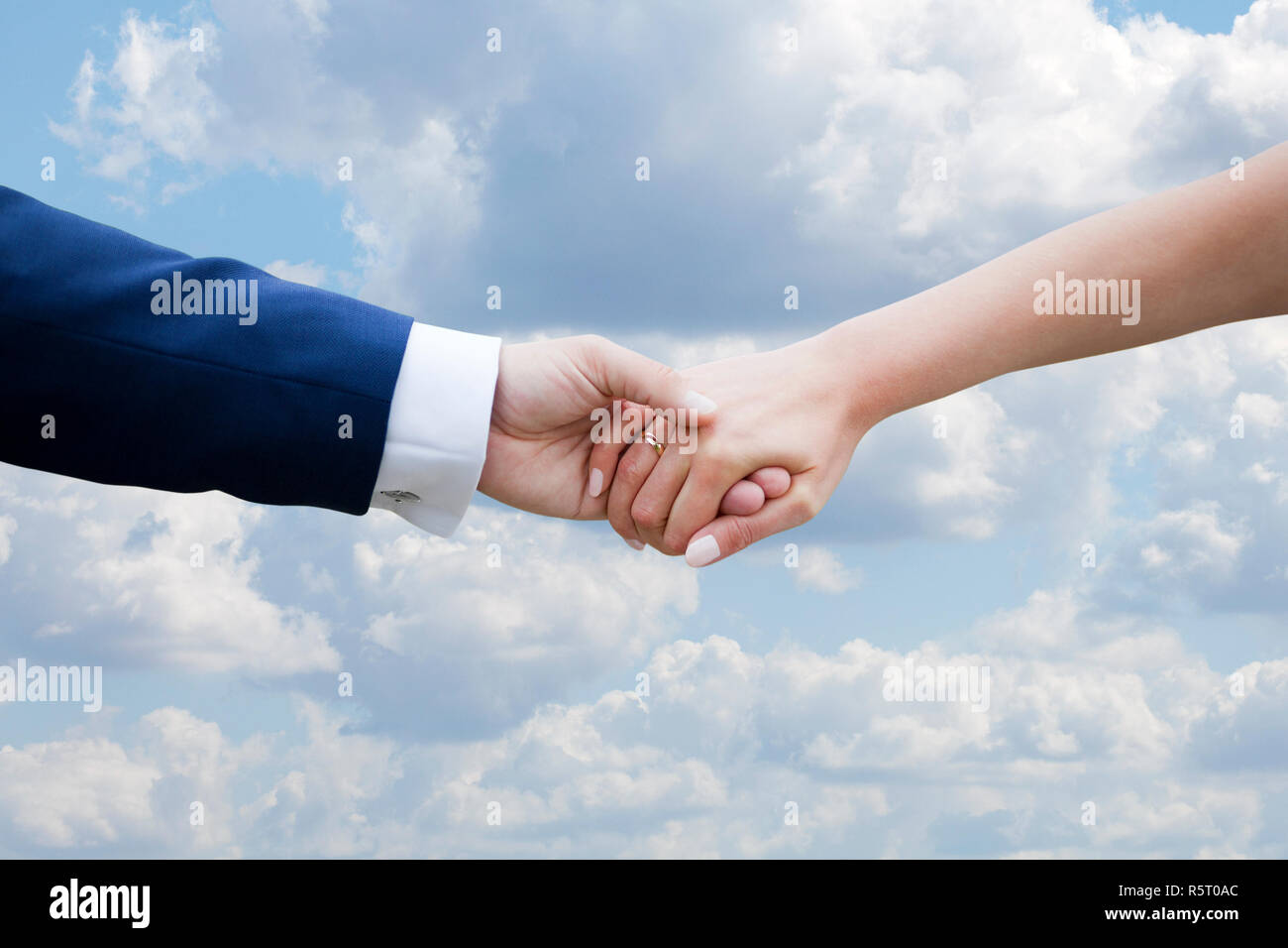 Wedding couple holding hands on blue sky with clouds Stock Photo - Alamy