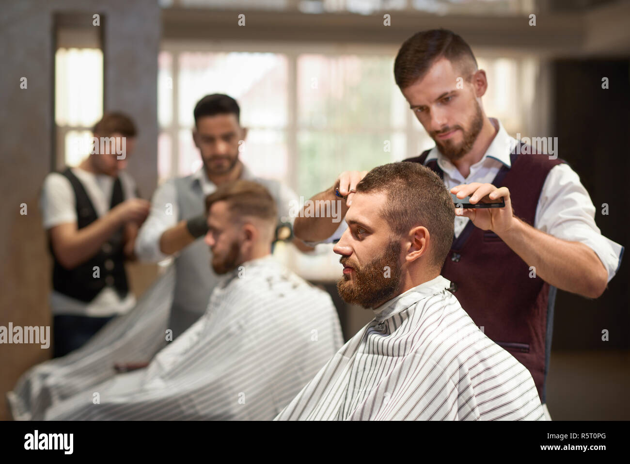 Side View Of Process Of Hairstyling In Barber Shop Young Bearded