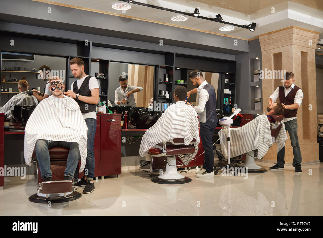 View from back of three barbers in white shirts and waistcoats